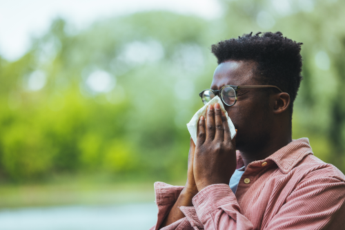 Man blowing his nose outdoors